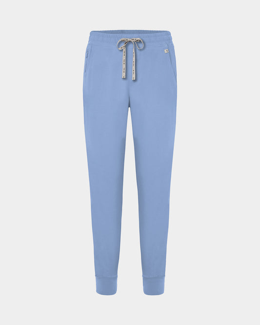 Light blue jogger scrub pants with a logo drawstring, ankle cuffs, and a small white logo on the left hip, shown against a light gray background.