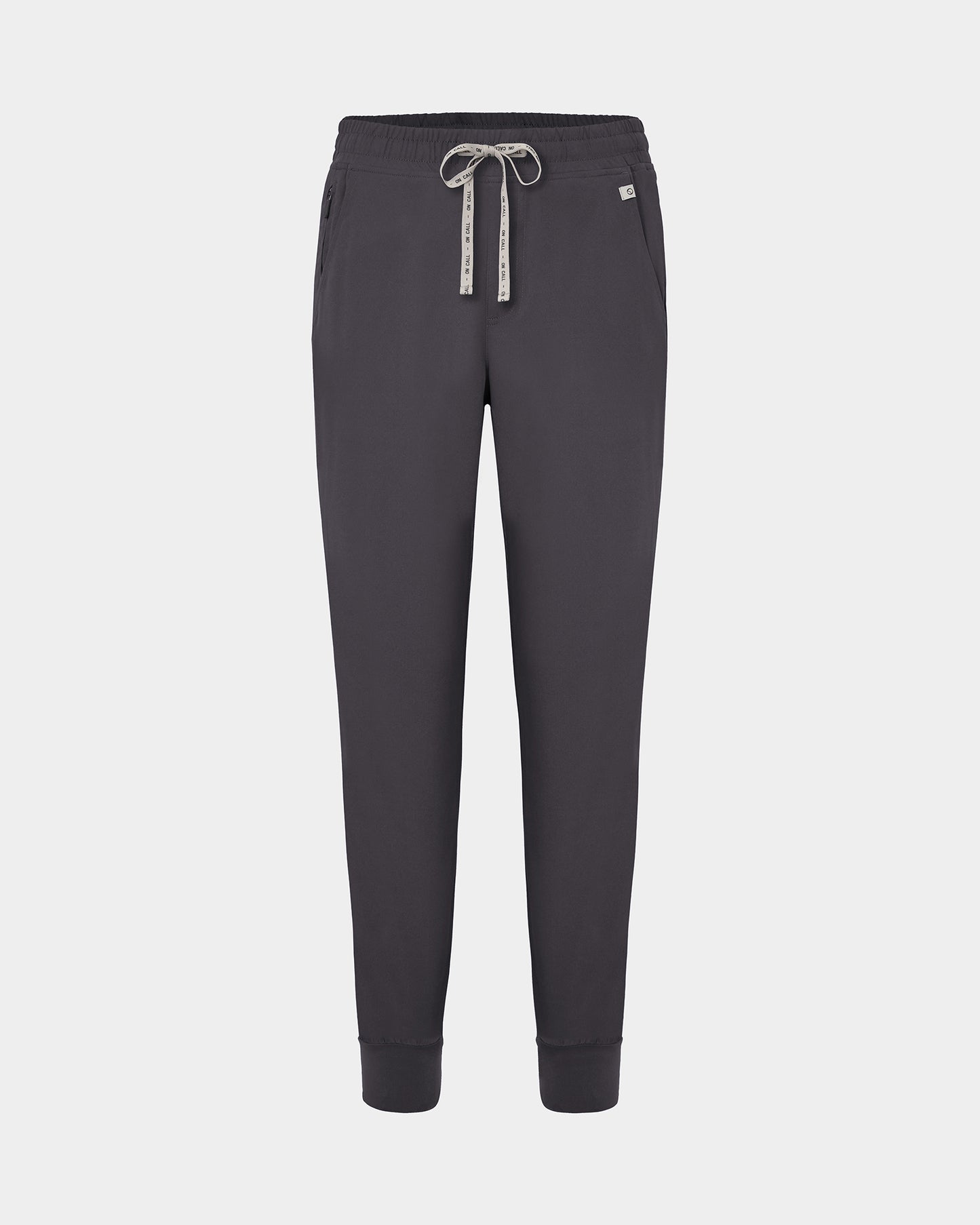Dark grey jogger scrub pants with a logo drawstring, ankle cuffs, and a small white logo on the left hip, shown against a light gray background.