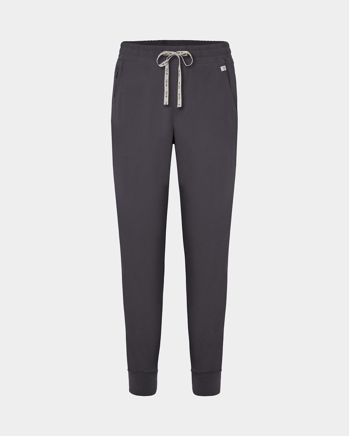 Dark grey jogger scrub pants with a logo drawstring, ankle cuffs, and a small white logo on the left hip, shown against a light gray background.