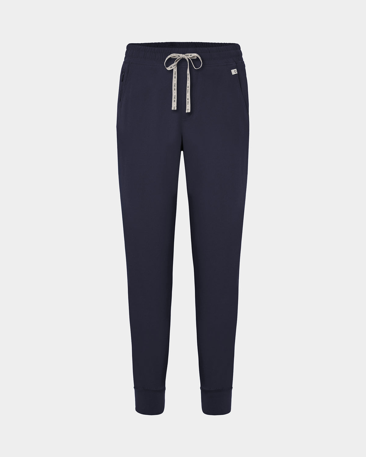 Navy jogger scrub pants with a logo drawstring, ankle cuffs, and a small white logo on the left hip, shown against a light gray background.