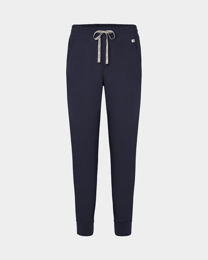 Navy jogger scrub pants with a logo drawstring, ankle cuffs, and a small white logo on the left hip, shown against a light gray background.