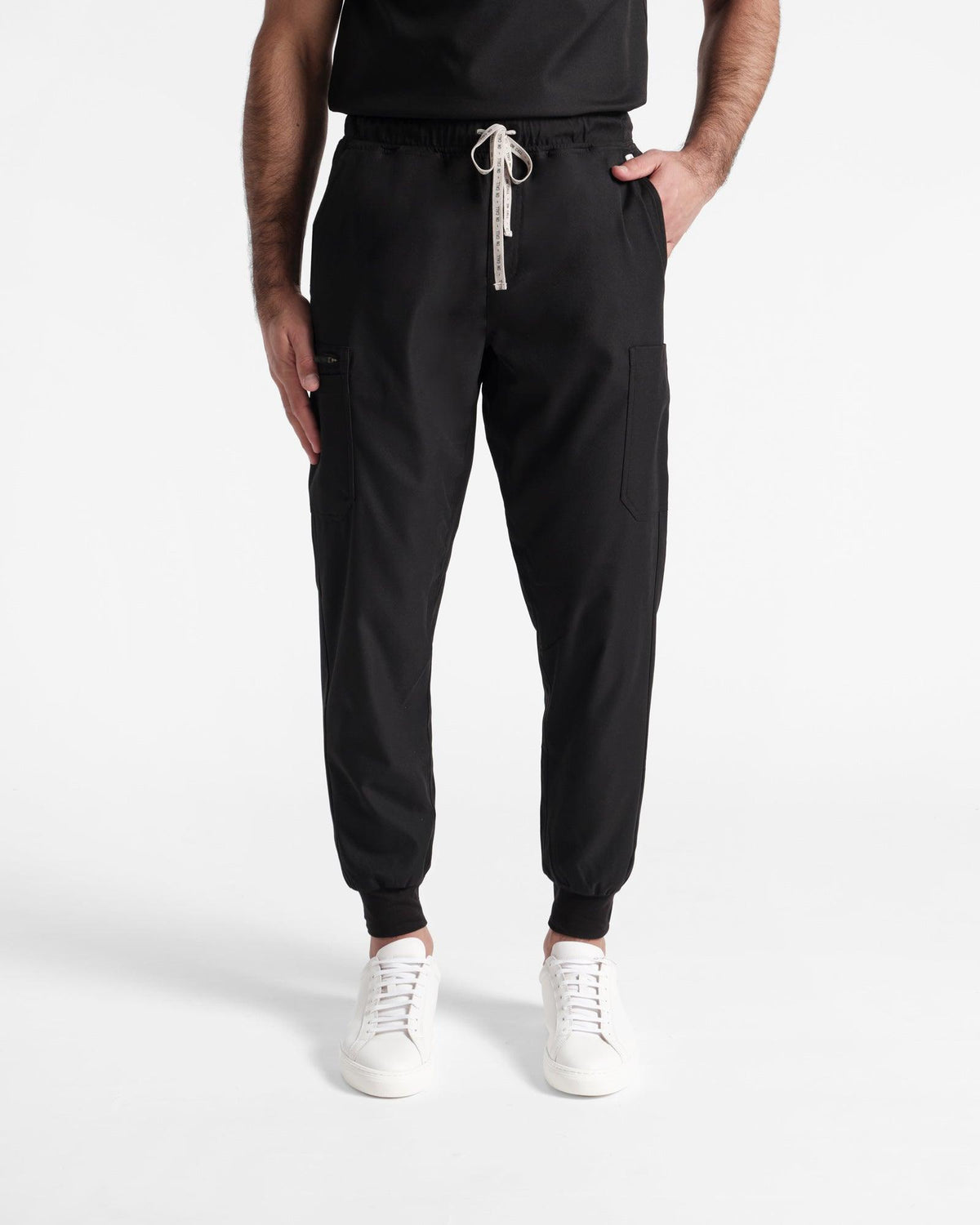 Model wearing men's black cargo jogger scrub pants with hand in pocket.