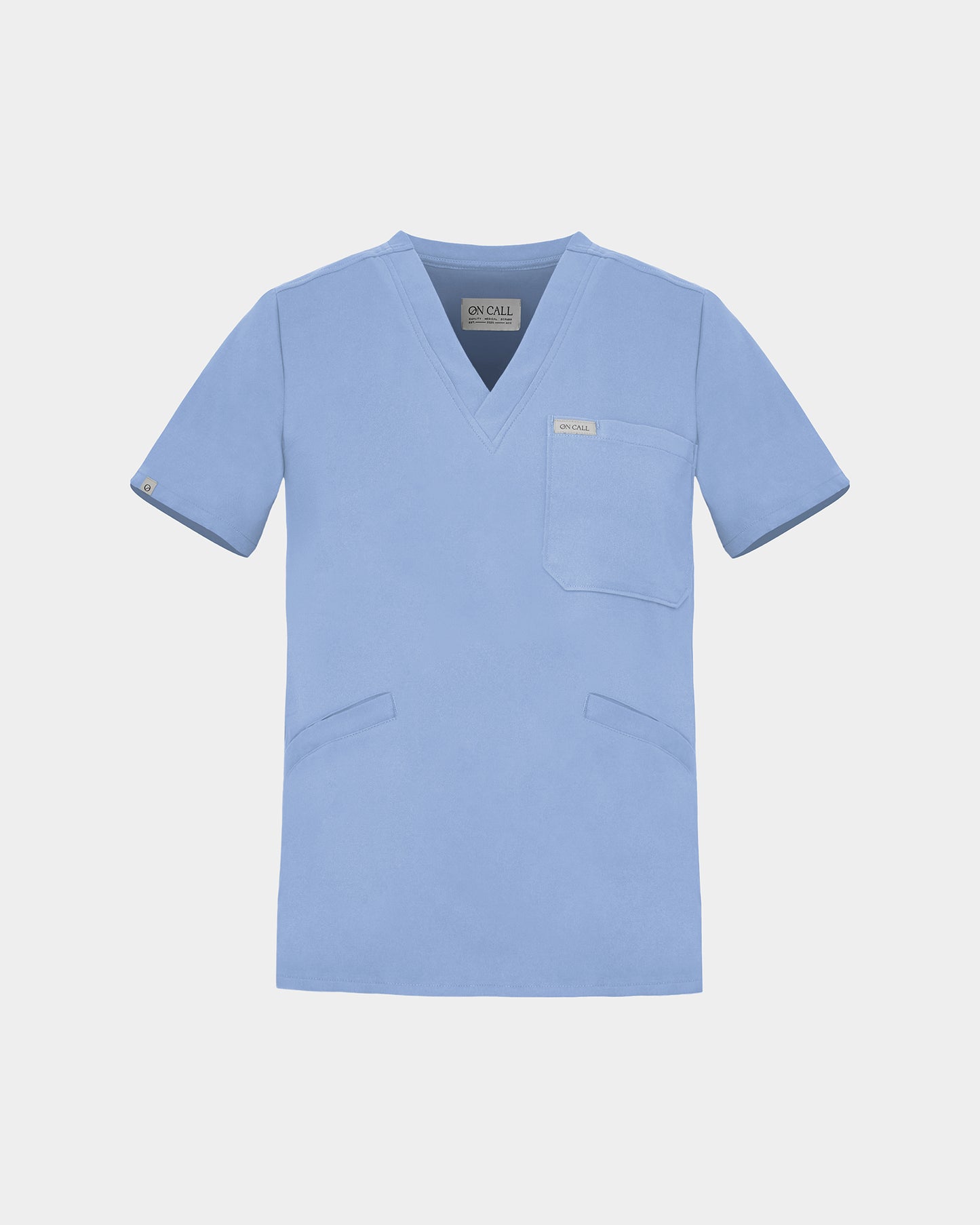 A light blue scrub top with a V-neck, short sleeves, a chest pocket, and two lower front pockets, shown on a light gray background.