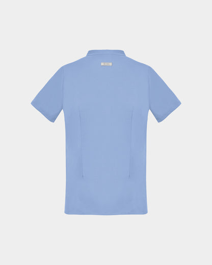 A light blue short-sleeve scrub shirt shown from the back, featuring two darts, centered on a light gray background.