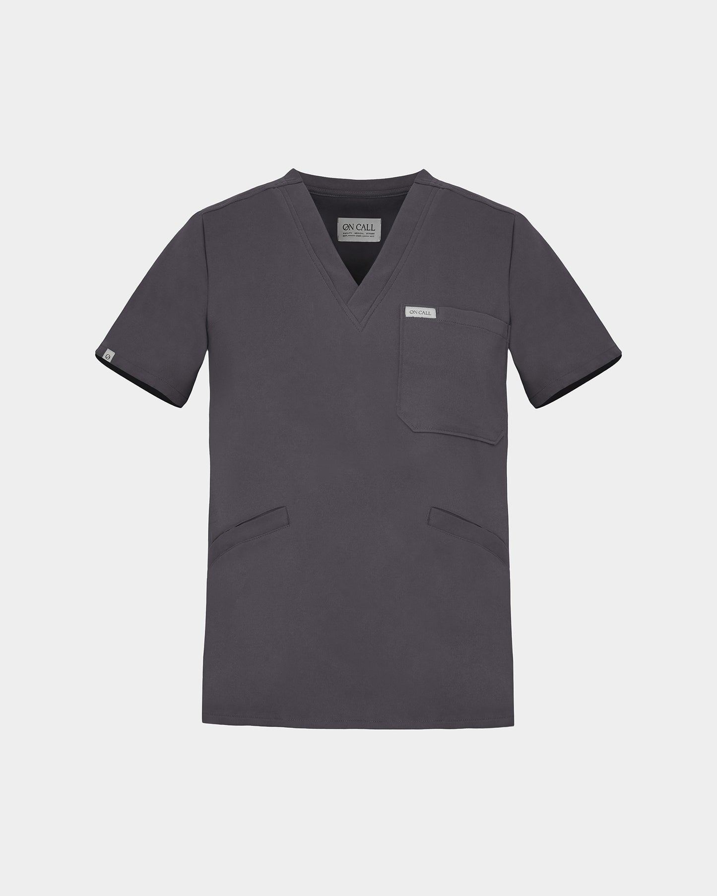 A dark grey V-neck scrub top with short sleeves, a chest pocket, and two lower front pockets, shown on a light gray background.