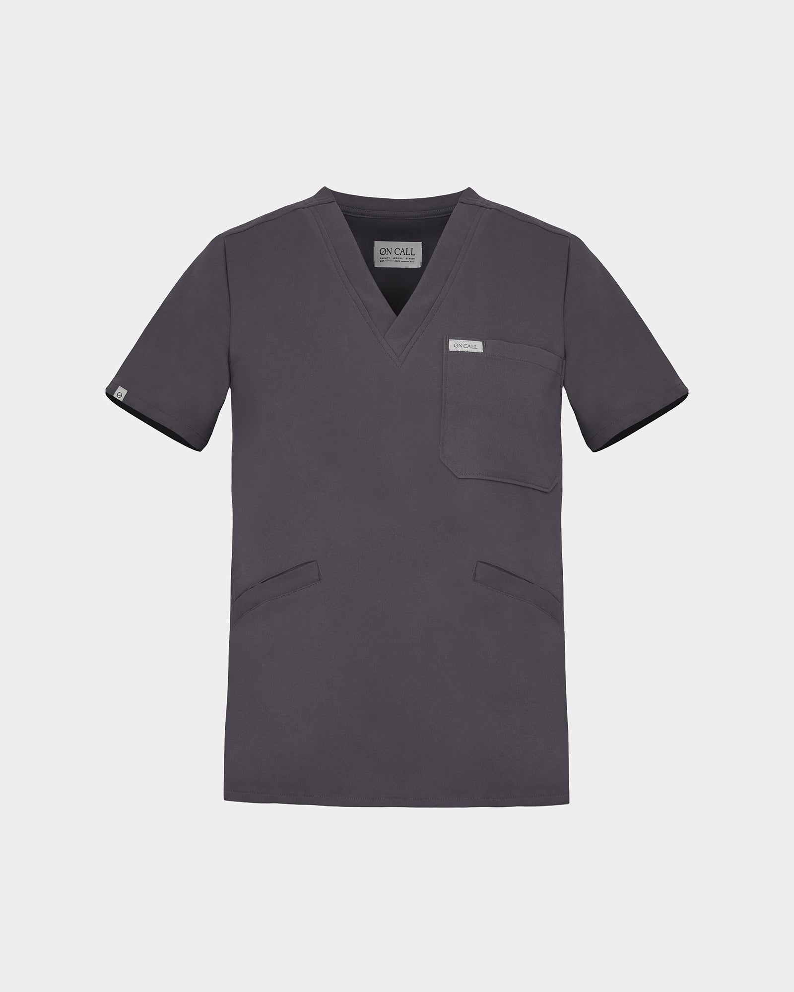 A dark grey V-neck scrub top with short sleeves, a chest pocket, and two lower front pockets, shown on a light gray background.