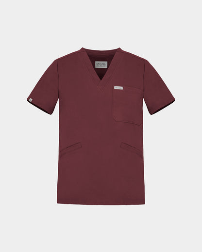 A v-neck scrub shirt in a dark heme red color, featuring a chest pocket and two additional lower pockets on the front.