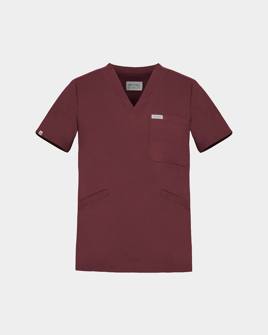 A v-neck scrub shirt in a dark heme red color, featuring a chest pocket and two additional lower pockets on the front.