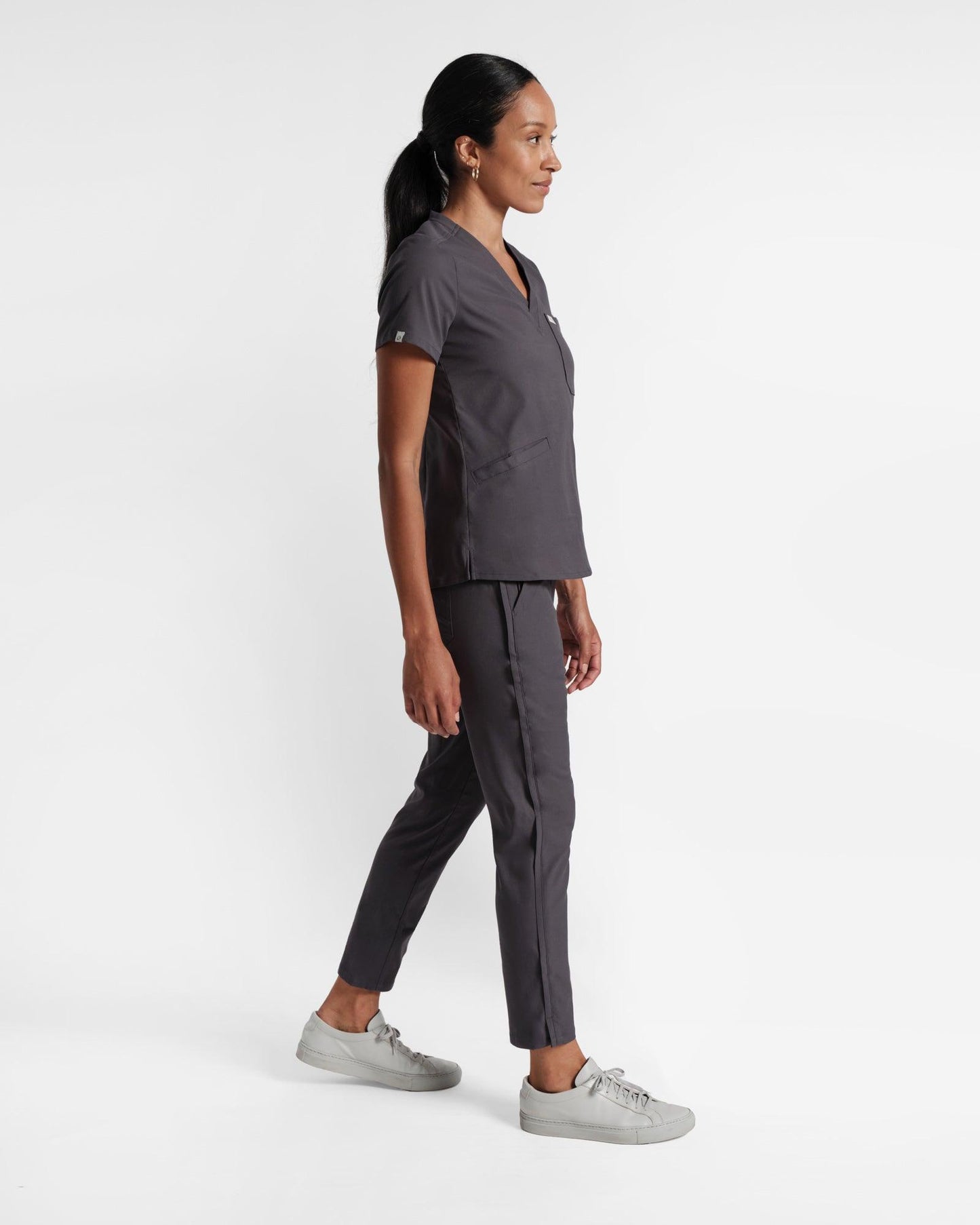 Side view of women's scrub top with three pockets in dark grey's